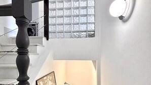 A staircase with a balustrade, a framed picture on the wall, a light fixture, and a window with a grid pattern.
