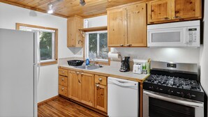 Una cocina funcional con armarios de madera, microondas, estufa y lavavajillas.