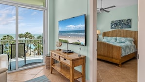 A bedroom with a view of the beach, a TV on a wooden console, and a ceiling fan. - Sapphire Condo & Spa Unit # 406 3 Bedroom Condo (South Padre Island)