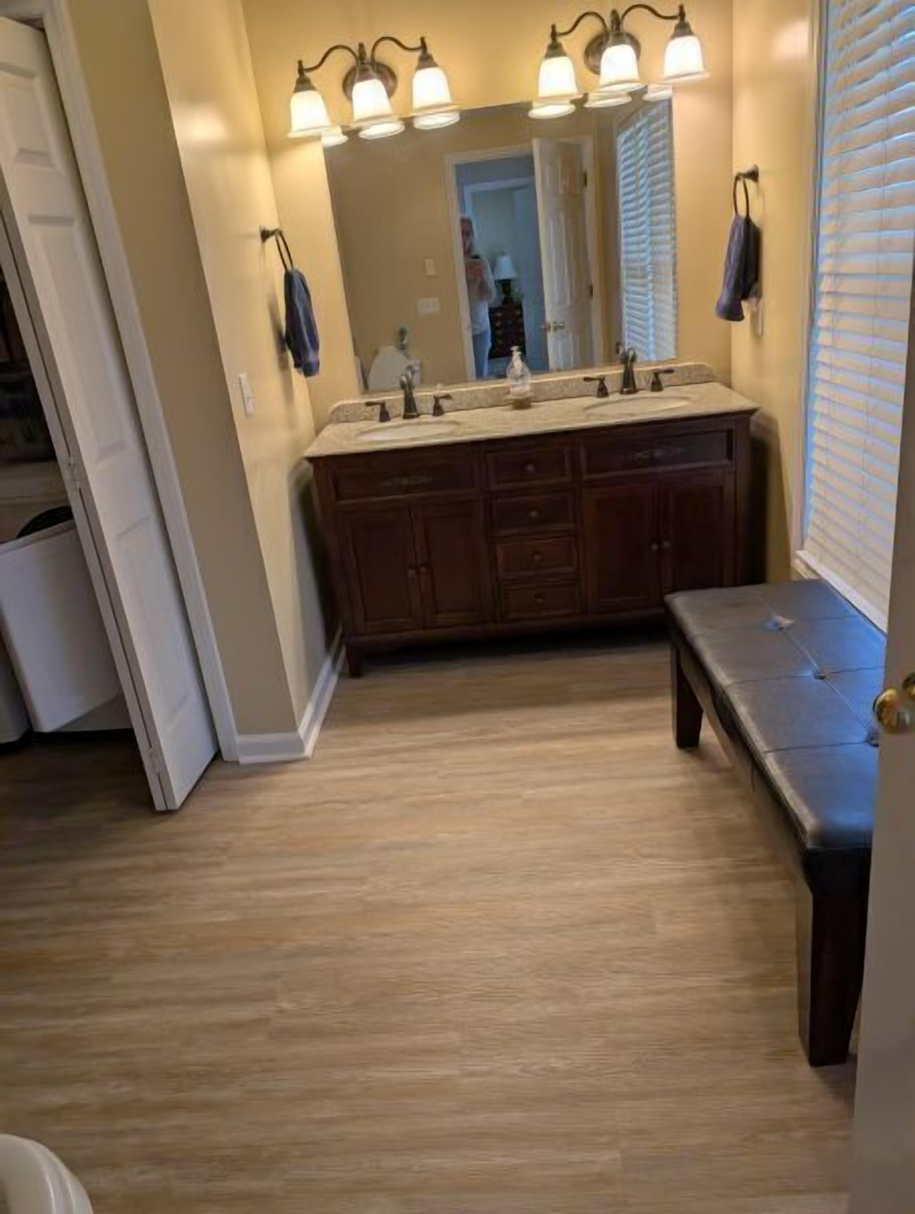 Un baño con tocador de madera, un espejo y un banco.