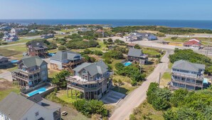 A coastal residential area with multiple two-story houses featuring balconies and a swimming pool. - Oceanside, Dog-Friendly Home in Rodanthe with Private Pool and Hot Tub (Rodanthe)