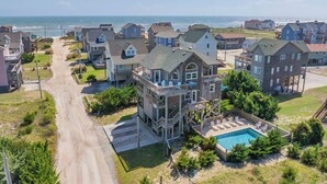 A coastal residential area with a prominent house featuring a large deck and a swimming pool. - Oceanside, Dog-Friendly Home in Rodanthe with Private Pool and Hot Tub (Rodanthe)