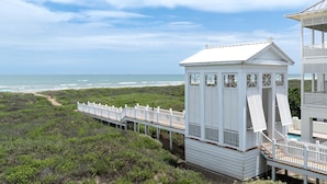 A beach house with a wooden deck and a small tower structure.