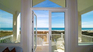 Ein Zimmer mit Glastür und Zugang zu einem Balkon mit Blick auf Strand und Meer.