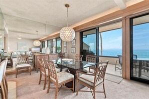 A modern dining area with a glass table and wicker chairs, overlooking a scenic ocean view. - Makena Surf, #f-206 2 Bedroom Condo (Kihei)