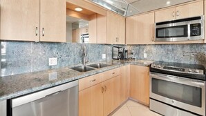 Una cucina moderna con piani di lavoro in granito, elettrodomestici in acciaio inossidabile e mobili in legno.