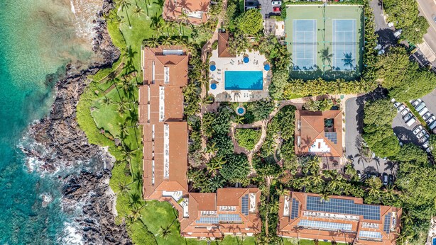 Vista aerea di una proprietà costiera con diversi edifici, una piscina e un campo da tennis.