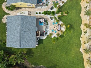 An aerial view of a property with a large building, a swimming pool, and a patio area with outdoor furniture. - Steps to Beach Patio Fire Pit Tropical Oasis (St. Augustine)