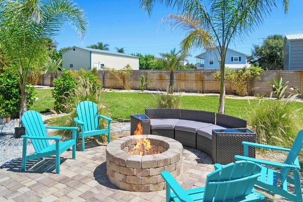 A backyard with a fire pit, outdoor seating, and a wooden fence. - Steps to Beach Patio Fire Pit Tropical Oasis (St. Augustine)