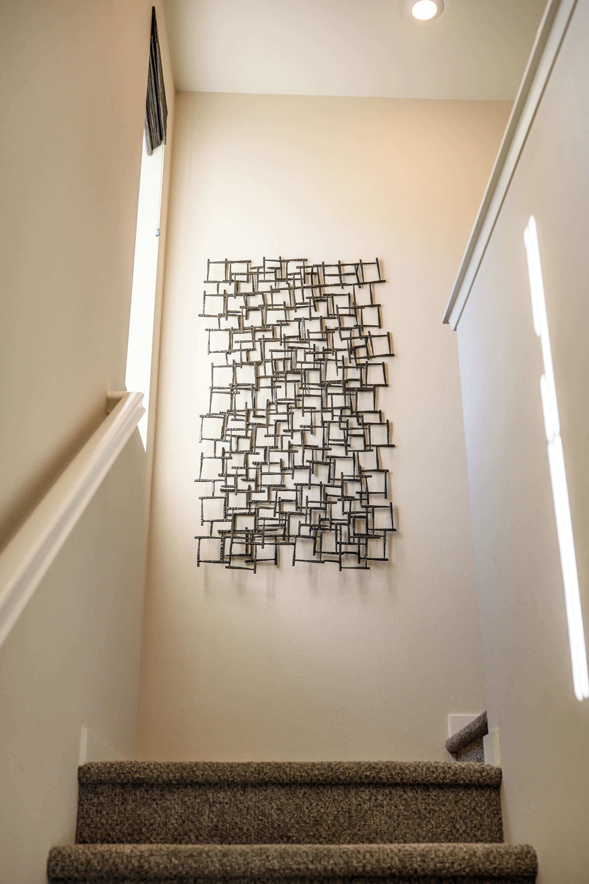 A staircase with a geometric wall art piece and carpeted steps.
