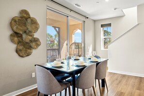 A dining area with a table set for six, a large decorative wall piece, and a view of the outdoors through a sliding door. - Designer 3BR El Monte Retreat Near Dtla Pasadena (El Monte)