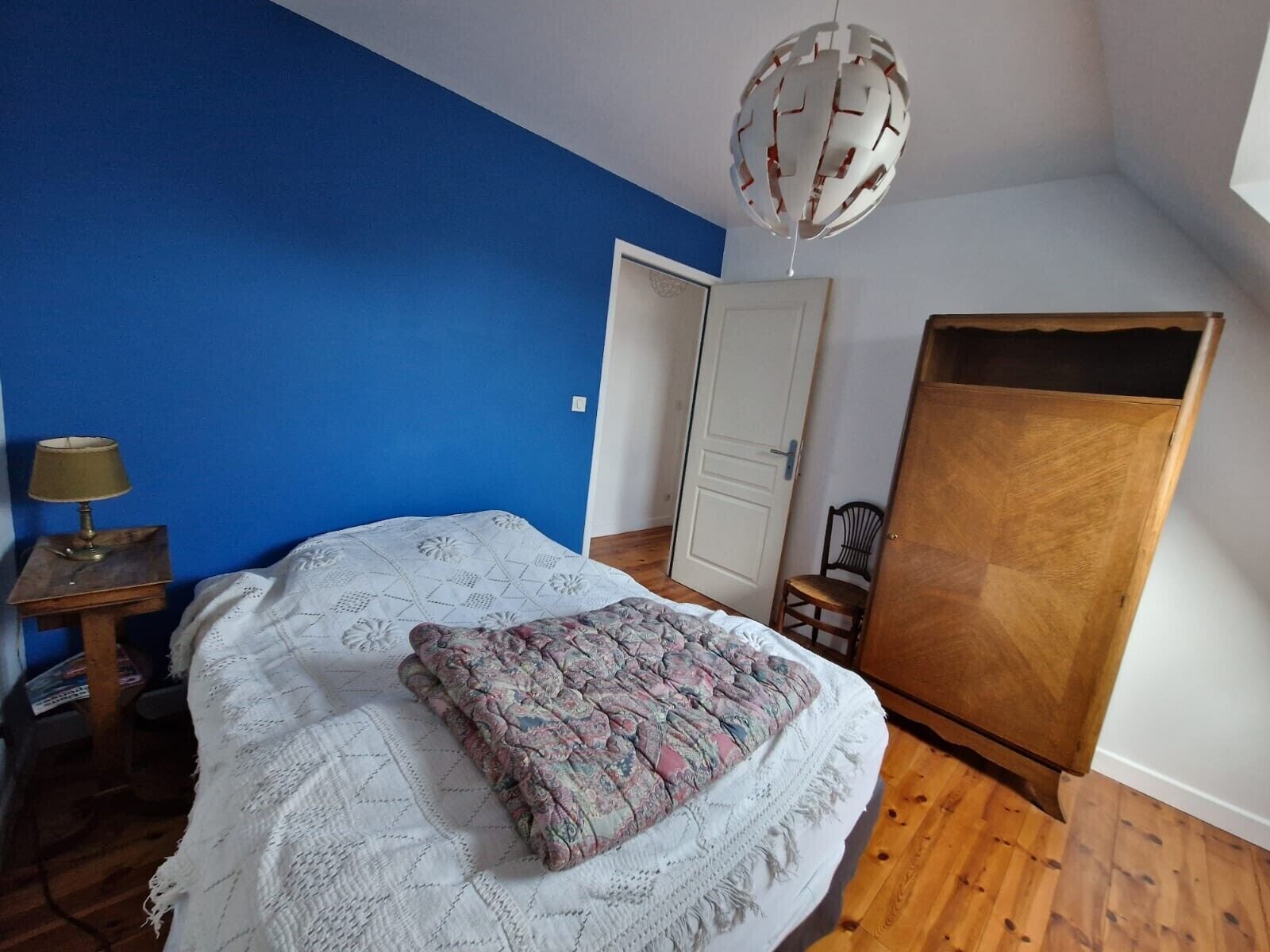 A bedroom with a bed, a lamp, a door, and a wardrobe.