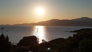 A sunset over a calm body of water with distant mountains.