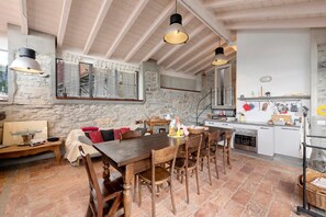Een landelijke keuken met een houten tafel, stoelen en een stenen muur.