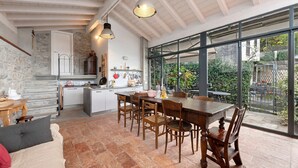 Cozinha espaçosa com área de refeições, janelas amplas e parede de pedra.