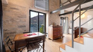Uma sala de jantar com mesa de madeira, cadeiras, vista para o exterior, escada e um armário de madeira.