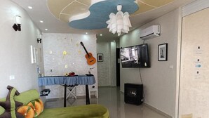 A modern living room with a green sofa, a guitar wall, a fireplace, and a television. - Guitar Palace (Bni Quolla)