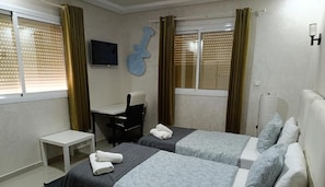 Ein Schlafzimmer mit zwei Betten, einem Schreibtisch, einem Stuhl und einer Gitarren-Dekoration an der Wand.