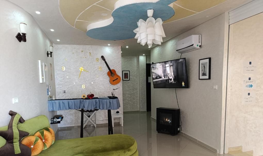 A modern living room with a green sofa, a guitar wall, a fireplace, and a television.