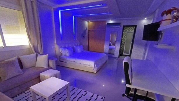Une suite moderne comprenant un lit, un canapé et un bureau, et se distinguant par un éclairage bleu original.