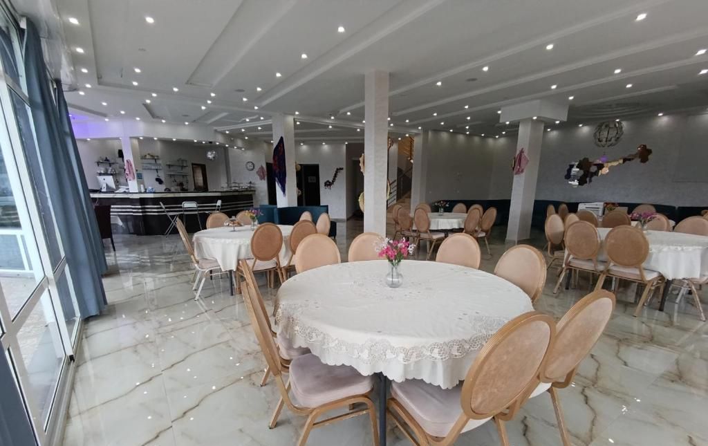 A restaurant interior with round tables, chairs, and a marble floor.