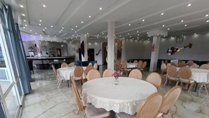 L’intérieur d’un restaurant avec des tables rondes, des chaises et un sol en marbre.