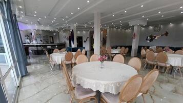 A restaurant interior with round tables, chairs, and a marble floor.
