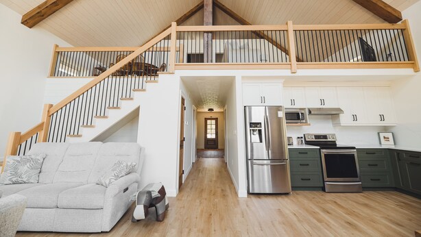 Un loft amplio con techos altos, una escalera de madera, una cocina con electrodomésticos modernos y un rincón de descanso acogedor.