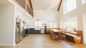 Una cocina amplia con piso de madera, estufa integrada y un comedor con sillas y banco de madera.