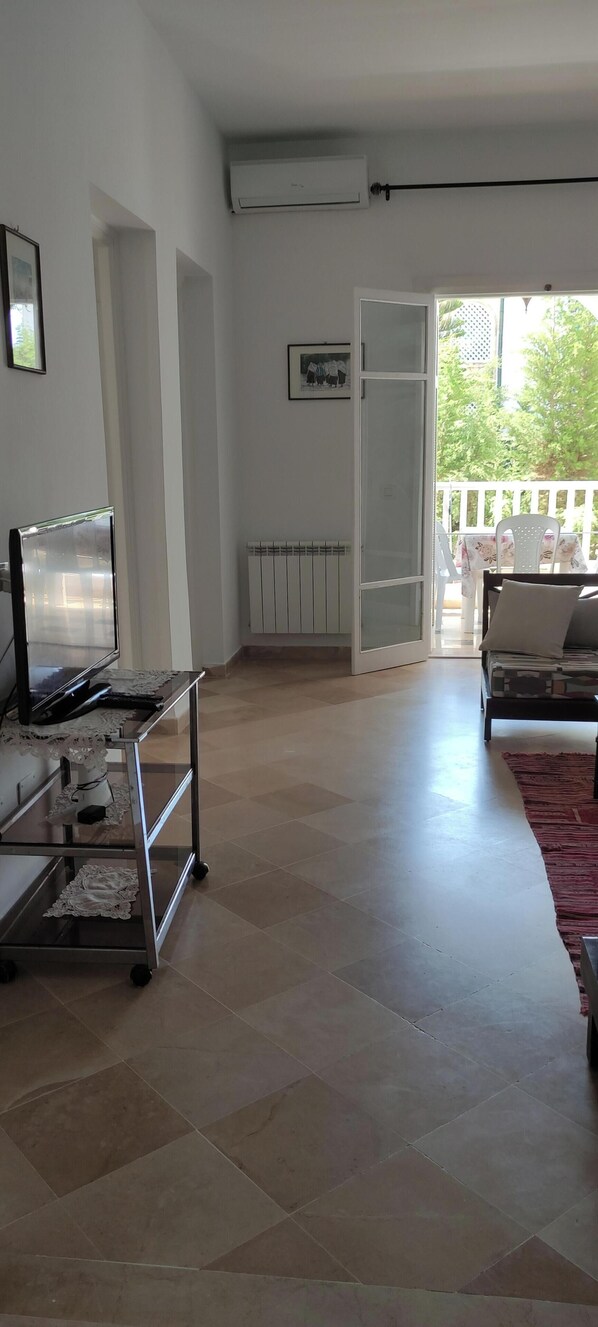 Un vaste espace de vie comprenant un téléviseur, une table basse en verre et un canapé.