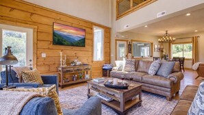 A spacious living room with a large painting, wooden walls, a sofa set, and a dining area.
