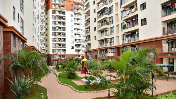 A multi-story residential building with balconies, a central courtyard with palm trees, and a playground.