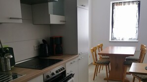 Une cuisine moderne dotée d’un îlot central, d’un four encastré et d’un coin repas avec une table et des chaises en bois.
