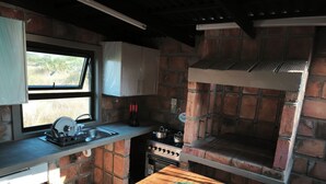 A compact kitchen with a window, a sink, a stove, and a brick oven.