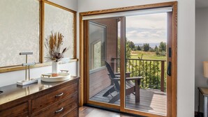 A bathroom with a wooden vanity, a large mirror, and a view of a deck and outdoor area.