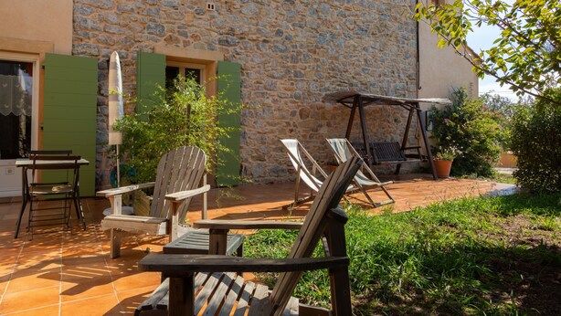 Edificio de piedra con un patio que incluye zona de estar al aire libre y un columpio.