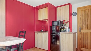 Una cocina compacta con una pared de acento roja, una puerta de madera y suelo de baldosas.