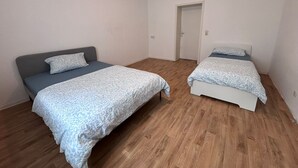 A room with two beds, each with a patterned bedspread and pillows, and a wooden floor. - Large flat with separate rooms for 8 guests STPh (Zeitz)