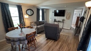 Ein Wohnzimmer mit Esstisch, Sofa und Fernseher.