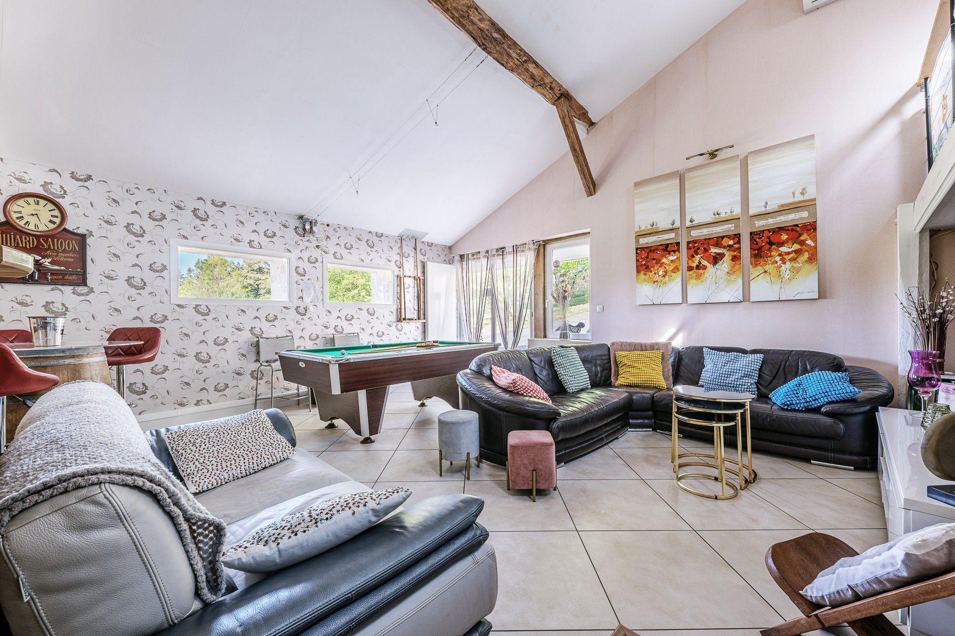 A spacious living area with a pool table, leather sofas, and a billiards cue rack.