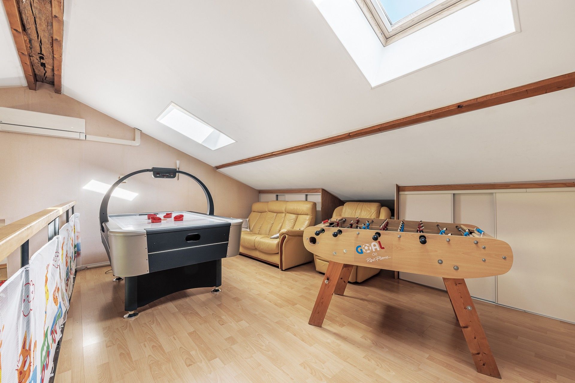 Ein Zimmer mit einem Kicker, einem Schreibtisch mit Lampe und einem Sofa.