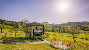 Ein rustikales Holzgebäude mit einem Bett, einem kleinen Tisch und einem Stuhl in einer grünen Wiese mit Blick auf sanfte Hügel.