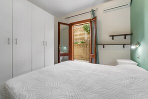 Une chambre à coucher comprenant un lit, une armoire et un petit balcon donnant sur un jardin.