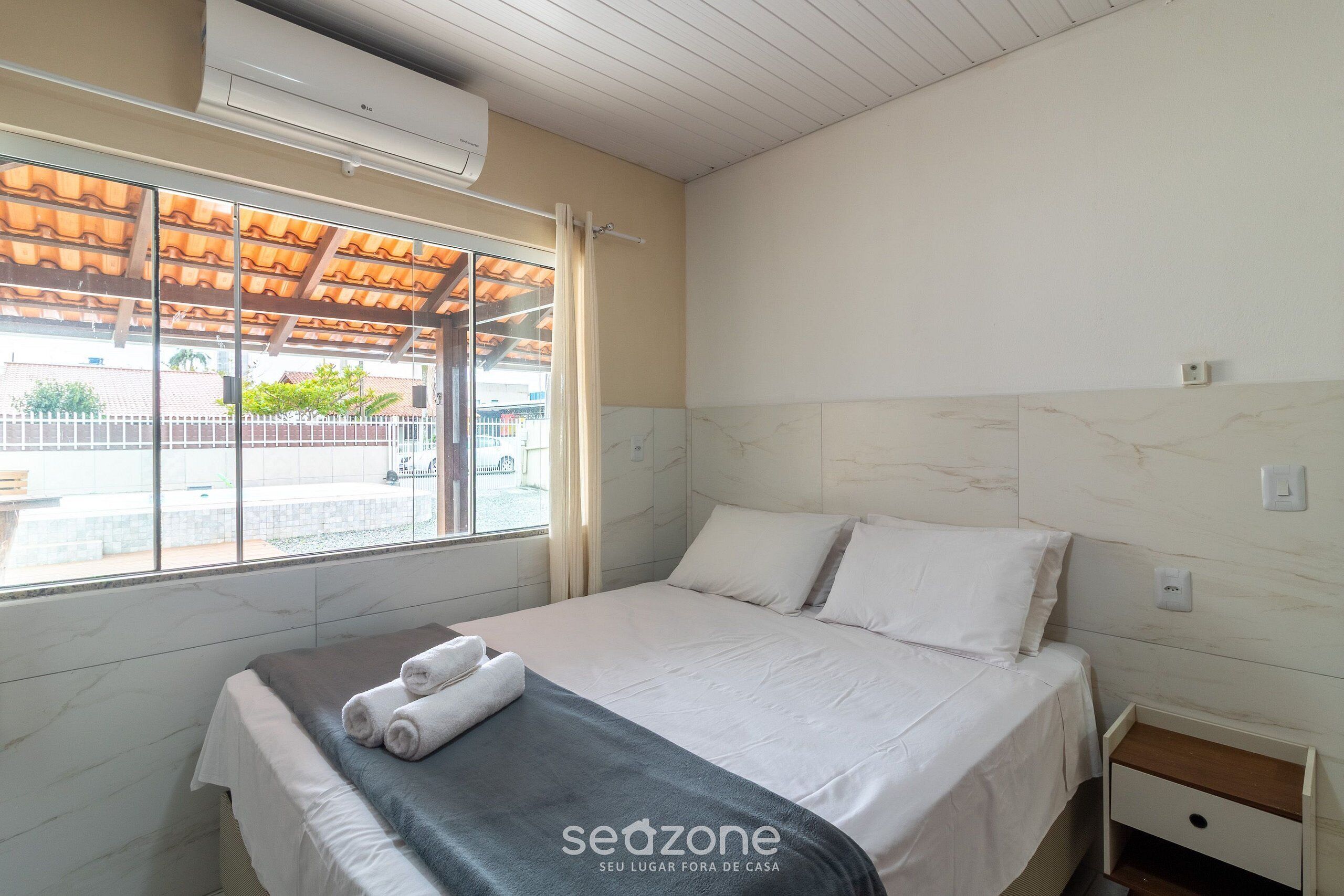 Une chambre d’hôtel avec un lit, une fenêtre donnant sur un paysage agréable et un ventilateur de plafond.
