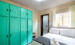 A hotel room with a bed, a large teal wardrobe, a window with curtains, and a small bedside table. - 4 BR House w/ Pool, 500m From Beto Carrero Jrs0130 (Penha)