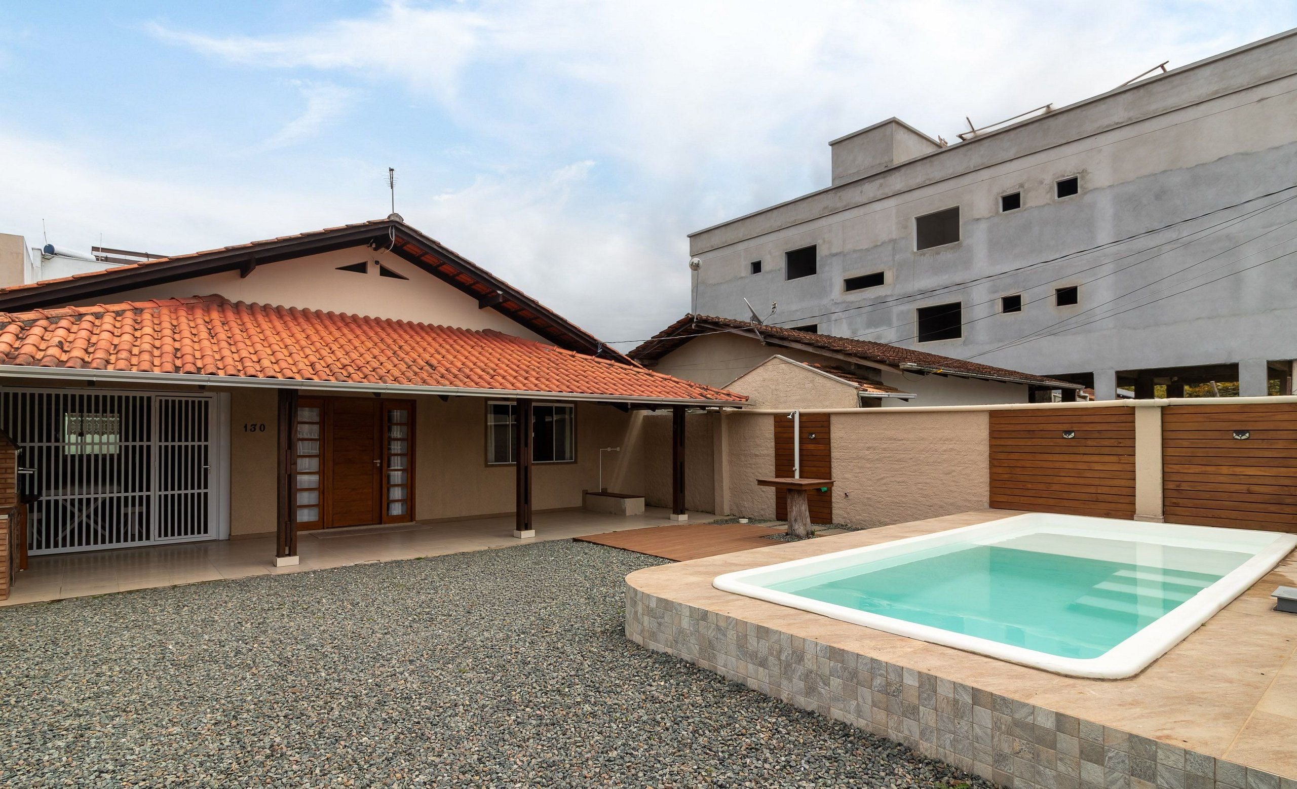 Une propriété résidentielle dotée d’une piscine, d’un patio couvert et d’une entrée sécurisée par un portail.