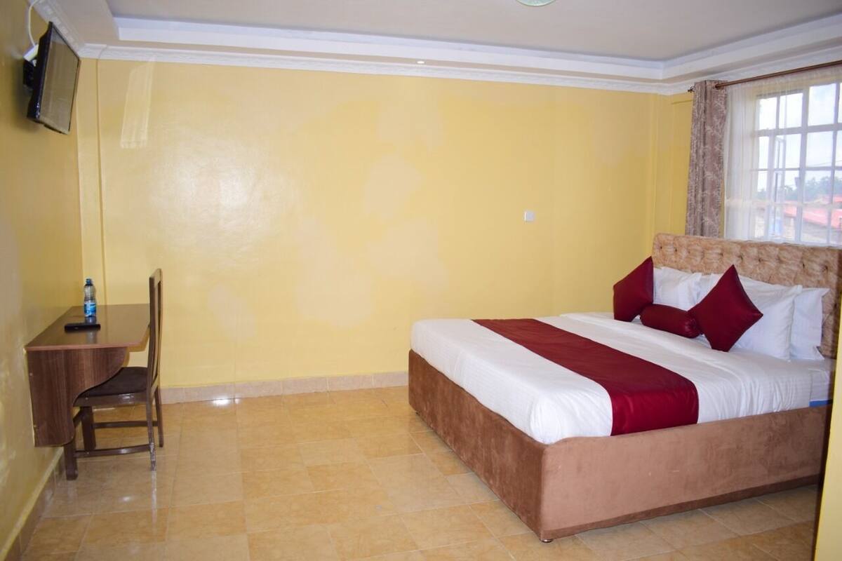 A hotel room with a bed, a desk, and a chair.