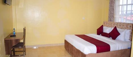 A hotel room with a bed, a desk, and a chair.