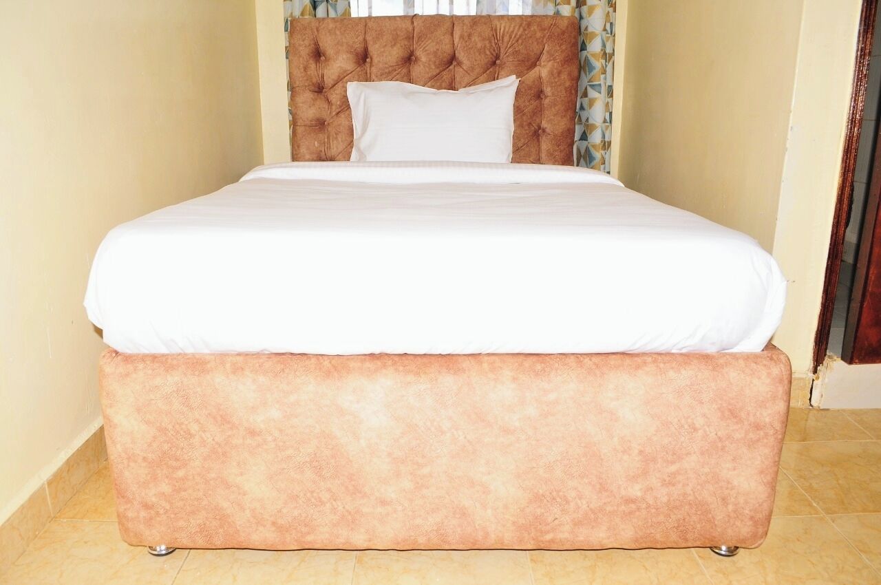 Una cama con cabecera capitonada y una almohada blanca.