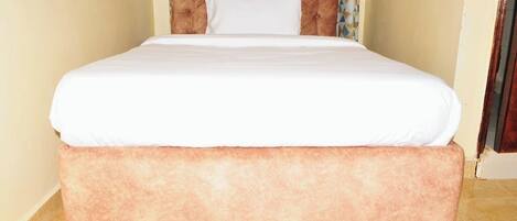 Una cama con cabecera capitonada y una almohada blanca.